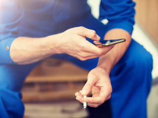 car service, repair, maintenance and people concept - auto mechanic smoking cigarette at workshop