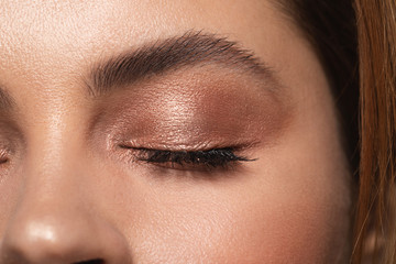 Closed eye of the woman with shiny eye shadows on the eyelid
