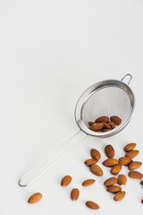 scattered almonds and sieve on grey background with copy space