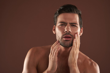 Young man focused on touching his bristle cheek