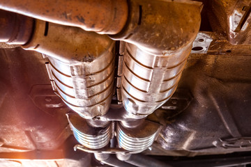 Fototapeta Extreme closeup of car exhaust pipes underneath the vehicle during repairs in a workshop obraz
