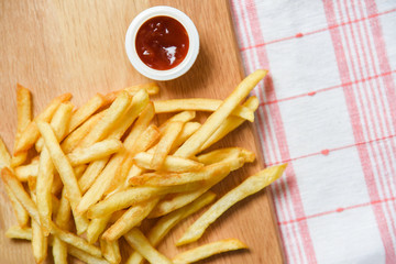 French fries on wooden board with ketchup on dining table