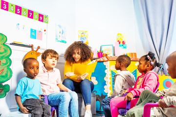 Group of kids listen teacher to read a story book