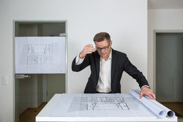 Der Bauherr bespricht sehr engagiert und gestenreich den ausgerollten Bauplan