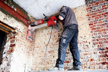 Laborer pierce a big round hole in a brick wall