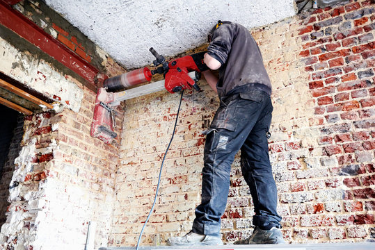 Laborer pierce a big round hole in a brick wall
