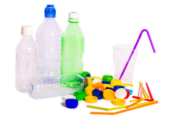 Plastic pollution. Plastic bottles, caps, straws and a glass isolated on white background
