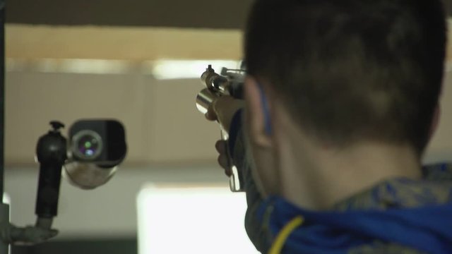 Professional young man aiming and shooting from a pneumatic pistol on the training in the dash.Closeup