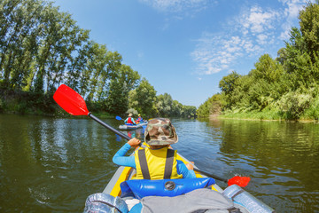 Happy boy kayaking on the river on a sunny day during summer vacation