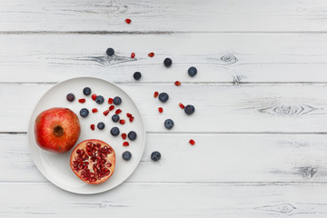 Fototapeta na wymiar blueberries and pomegranate on a plate on distressed white wood