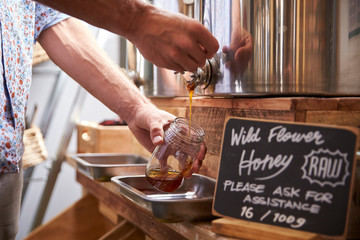 Man Filling Container With Wild Honey In Sustainable Plastic Free Grocery Store
