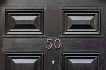 Fifty on an elegantly panelled wooden house door 