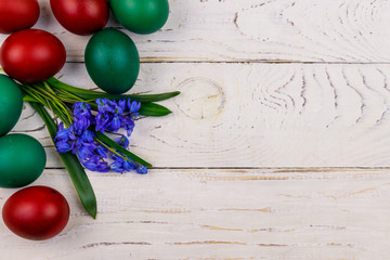 Painted Easter eggs and blue scilla flowers on white wooden background. Easter composition. Top view, copy space