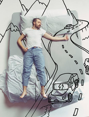 Hitch-hiking on the road. Top view photo of young man sleeping in a big white bed at home. Dreams...