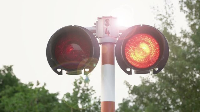 Two railway crossing signal pulsating in red. On the shot you can see a bright glow in the lens.