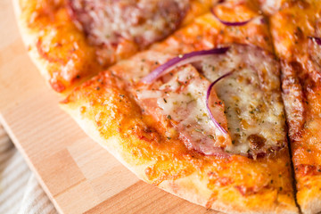 food, culinary and eating concept - close up of sliced homemade pizza on wooden table