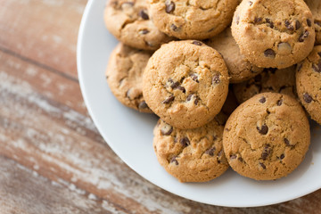 food, junk-food and eating concept - close up of oatmeal cookies with chocolate chips on plate