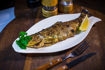 Baked mackerel with lemon and parsley on a white plate
