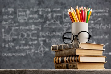 Stack of books with pencils and glasses on  table
