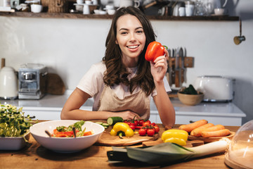 Beautiful young woman wearing apron cooking vegetables