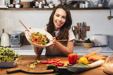 Beautiful young woman wearing apron cooking vegetables