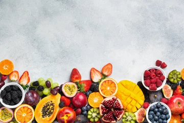 Fotobehang Healthy raw rainbow fruits background, mango papaya strawberries oranges passion fruits berries on oval serving plate on light kitchen top, top view, copy space, selective focus © Liliya Trott