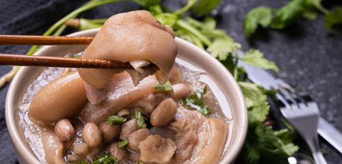 Top view, close up, copy space, Taiwan asian distinctive street food, peanut pork knuckle soup in a beige ivory creamy-white colored bowl isolated on dark shale slate table