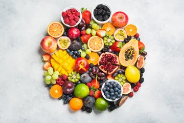 Selbstklebende Fototapeten Circle made of healthy raw rainbow fruits, mango papaya strawberries oranges passion fruits berries on oval serving plate on light concrete background, top view, copy space, selective focus © Liliya Trott