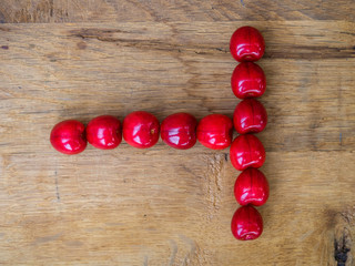  cherry on wooden background as a letter