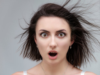 Conceptual portrait of a stylish brunette girl on a white background with flowing hair. Fashionable photo of beautiful girl with dark hair