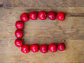  cherry on wooden background as a letter