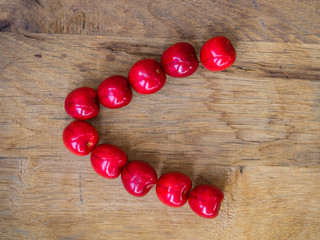  cherry on wooden background as a letter