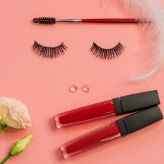 Obraz premium Eyelashes, powder eyebrow brush and lipstick as a beautiful face, concept on pink background.