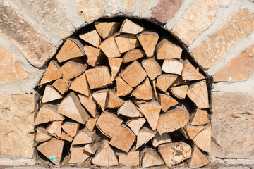 Brennholz lagert unter gemauertem Ofen