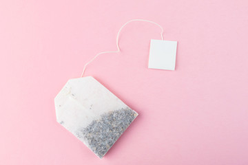 Tea bags with white labels on the background of pastel pink surface. Bright image is suitable as a background, there is an empty space for text or logo. Top view