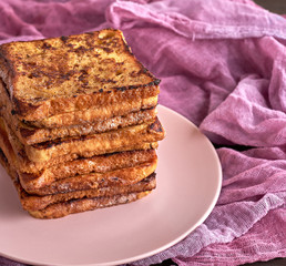 stack of square pieces of fried bread slices on a pink ceramic round plate