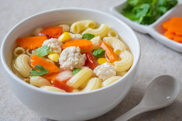 Macaroni chicken meatball soup in bowl .