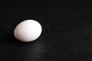 A white egg on the black slate platter
