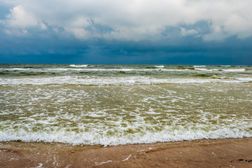 empty sea beach before storm with dramatic clouds and shadows from trees on the sand