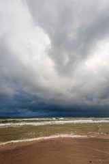 empty sea beach before storm with dramatic clouds and shadows from trees on the sand
