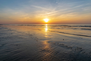 Fototapeta premium orabge colored sunset over calm sea beach water fields