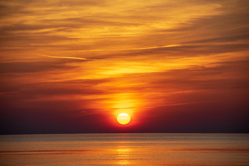 orabge colored sunset over calm sea beach water fields
