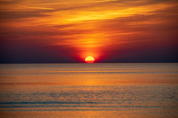 Obraz premium orabge colored sunset over calm sea beach water fields