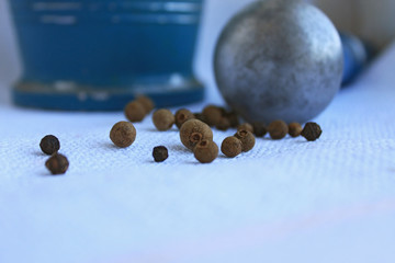 Black peppercorns in ancient metal mortar with pestle on linen background