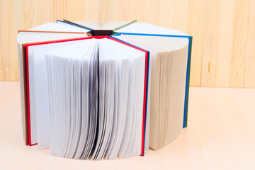 Open book, stack of hardback books on wooden table. Back to school. Copy space