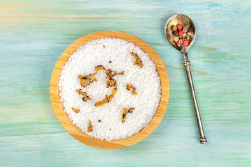 Gourmet spices. A bowl of sea salt infused with truffle shavings and a mix of peppercorns, shot from the top on a teal blue background with copy space