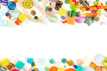 Many different beads, shot from the top on a white background, forming a frame for copy space