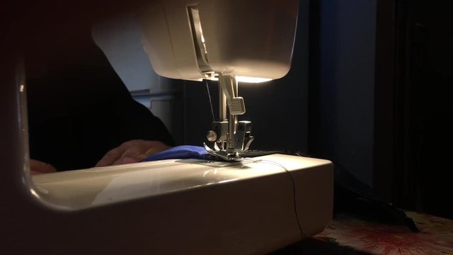 Person stitches cloth on the sewing machine. Cratches the thread on the fabric.