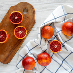 Whole and halved blood oranges on a white wooden background, view from above. Flat lay, overhead,...