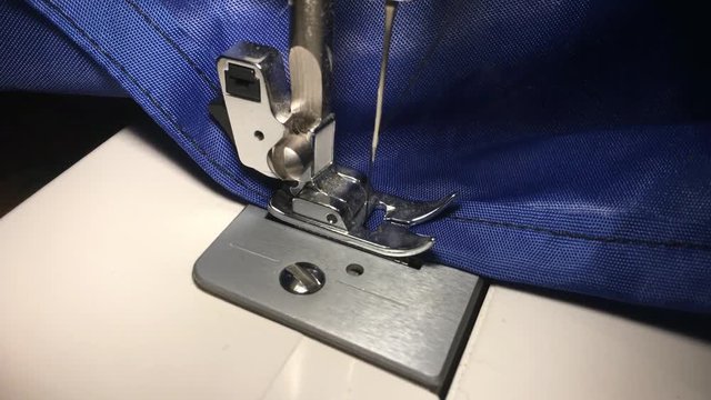 Person stitches cloth on the sewing machine. Cratches the thread on the fabric.